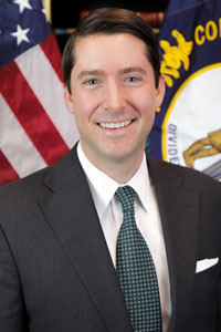 Portrait of Michael Wilson in front of the American and Kentucky flags.